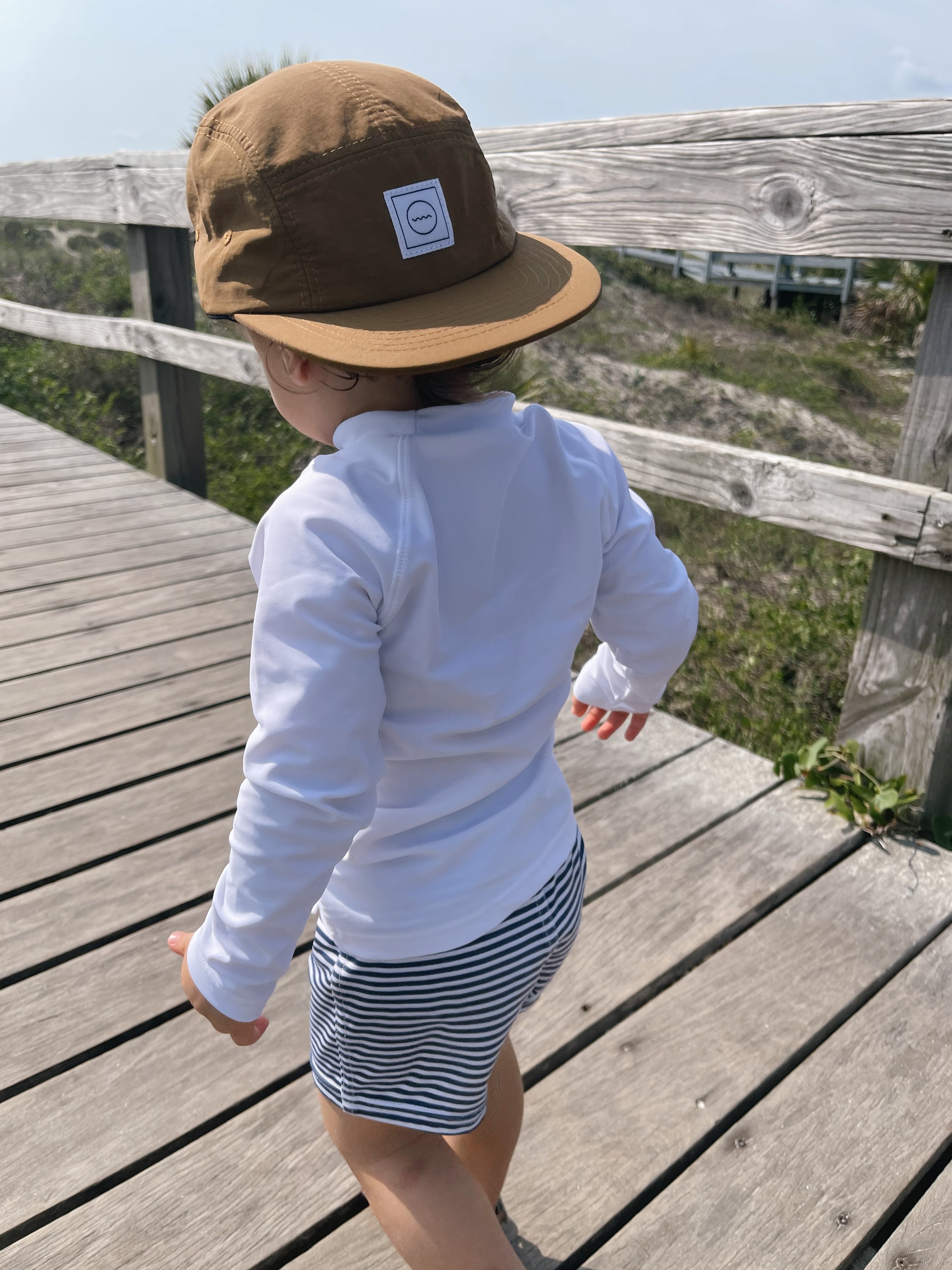 Waterproof Clay Five-Panel Hat on toddler walking on the boardwalk 